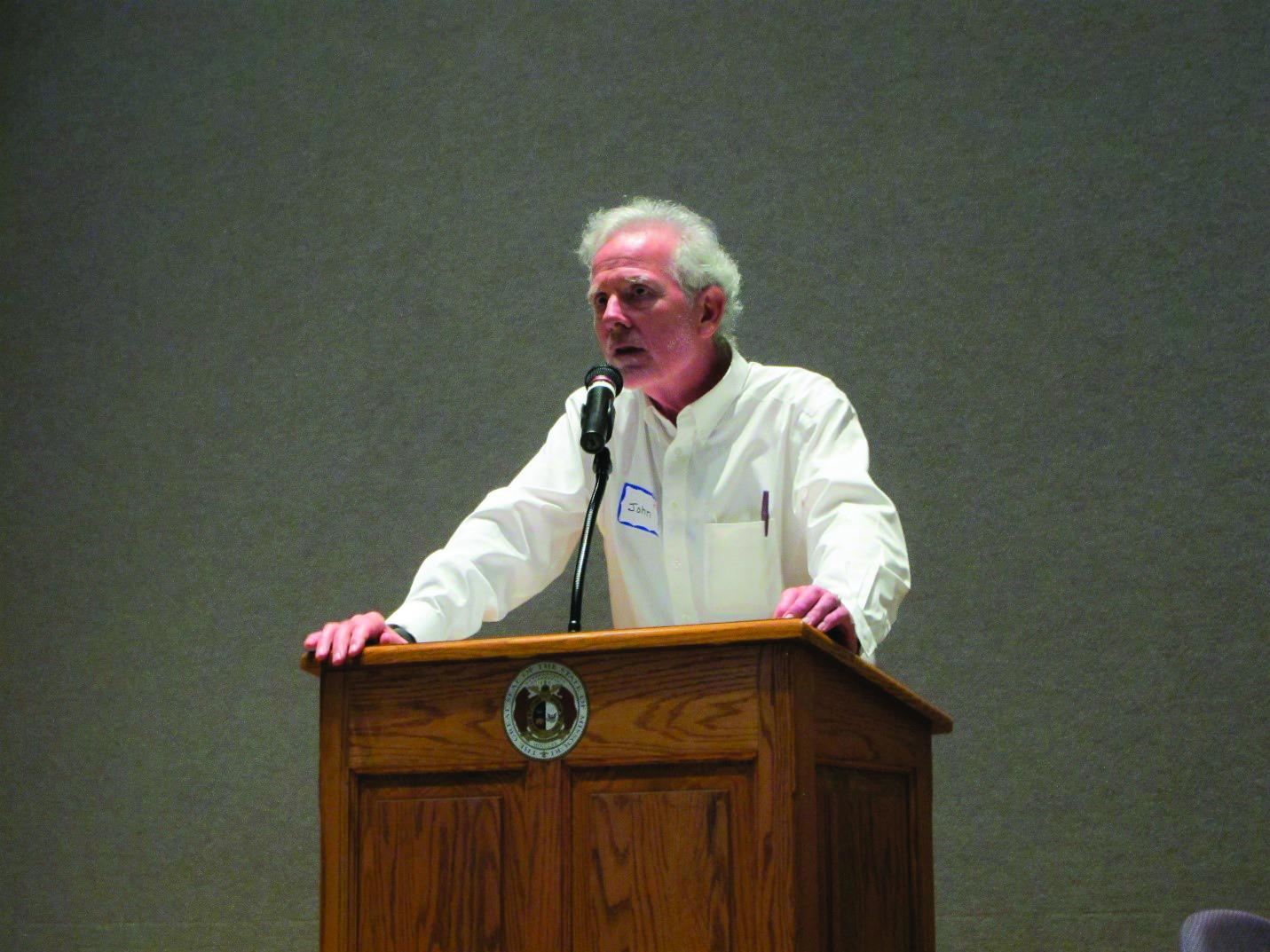 A photo of John Drake Robinson behind a podium