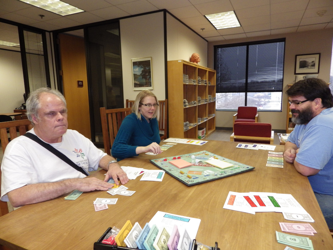 Three Wolfner Staff members playing Print/Braille Monopoly
