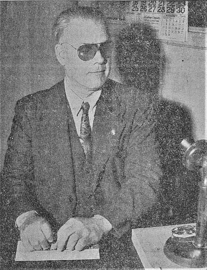 A grainy photo of Edward Endicott at a desk, speaking into a microphone.
